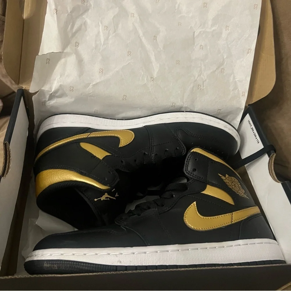 Nike Air Jordan 1 Mid in the black, metallic gold, and white colorway